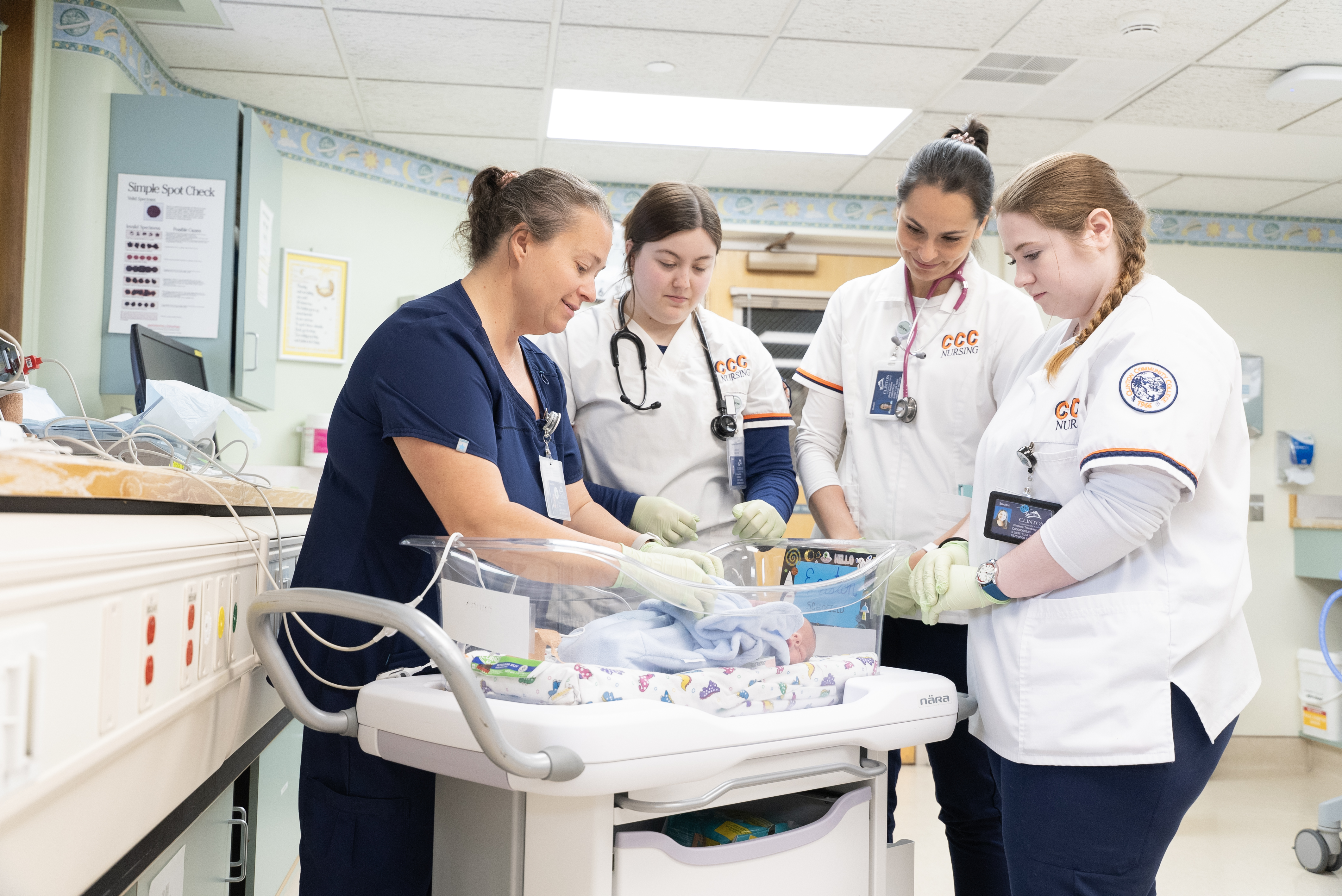 Champlain Valley Physicians Hospital labor and delivery nurse works with Clinton Community College students on taking care of a newborn baby.
