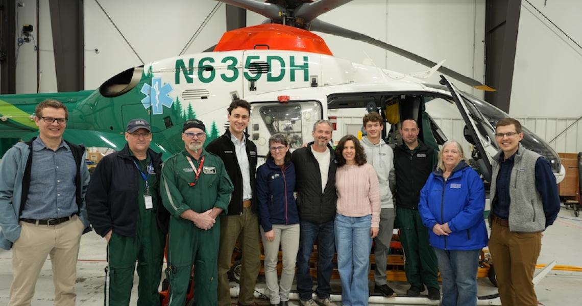 Stahl Family and UVM Health Network staff pose in front of hospital helicopter.