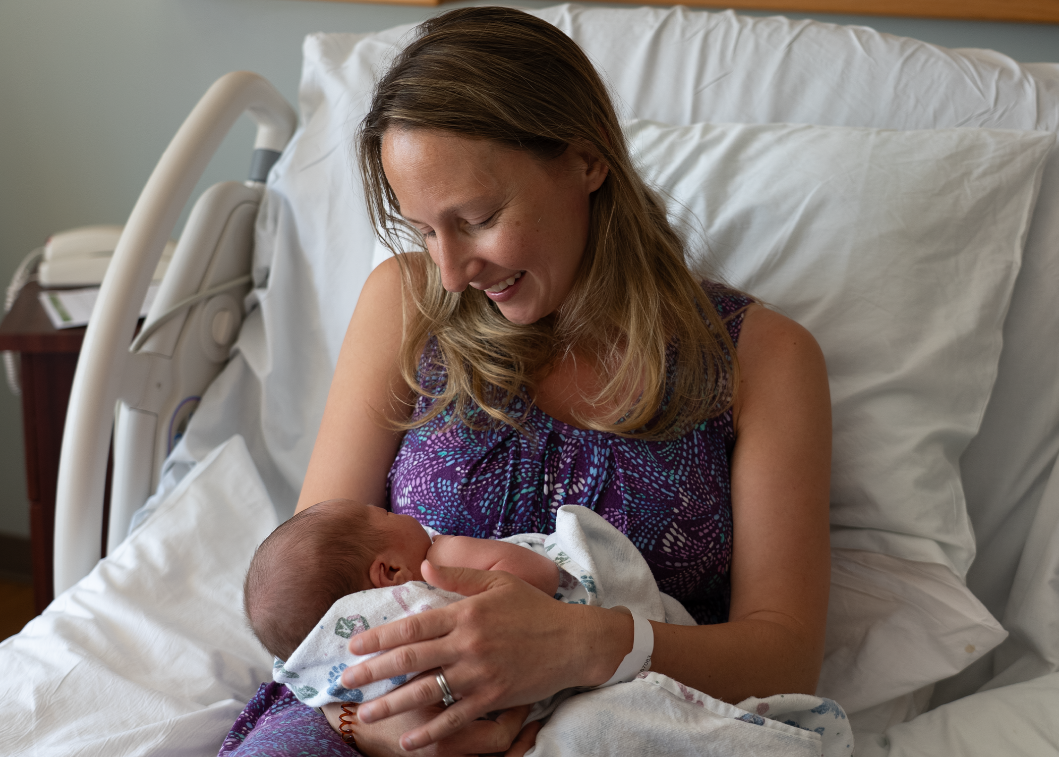 A patient holds their newborn baby in bed.