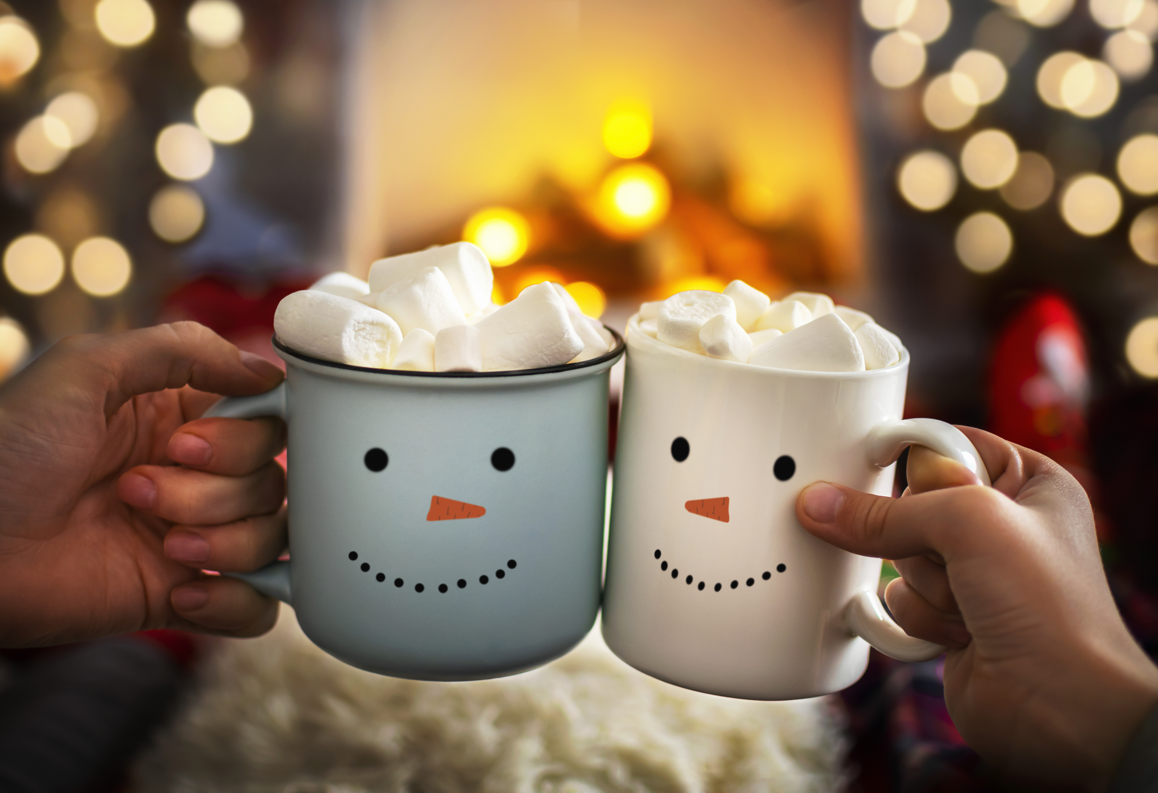 Two snowman face mugs of hot chocolate topped with marshmellows.