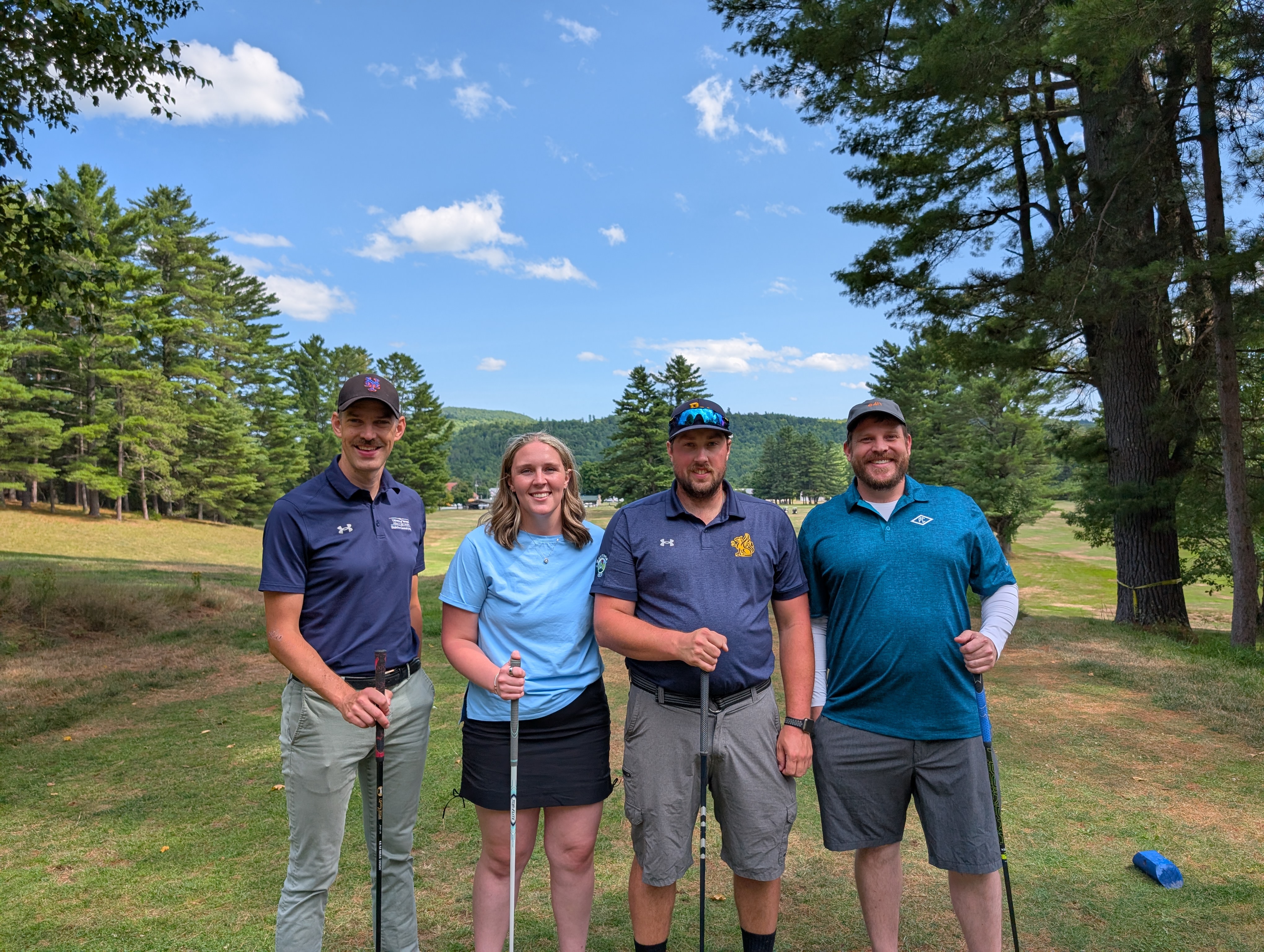Four golfers smile at the camera.