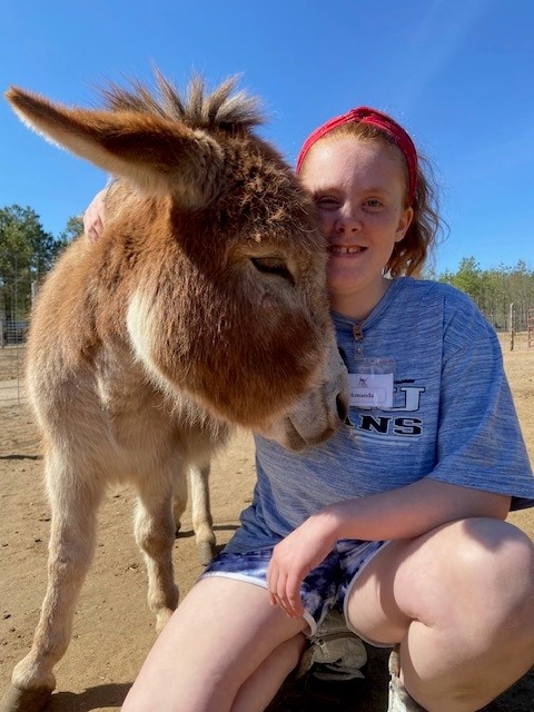 A girl poses with a donkey.