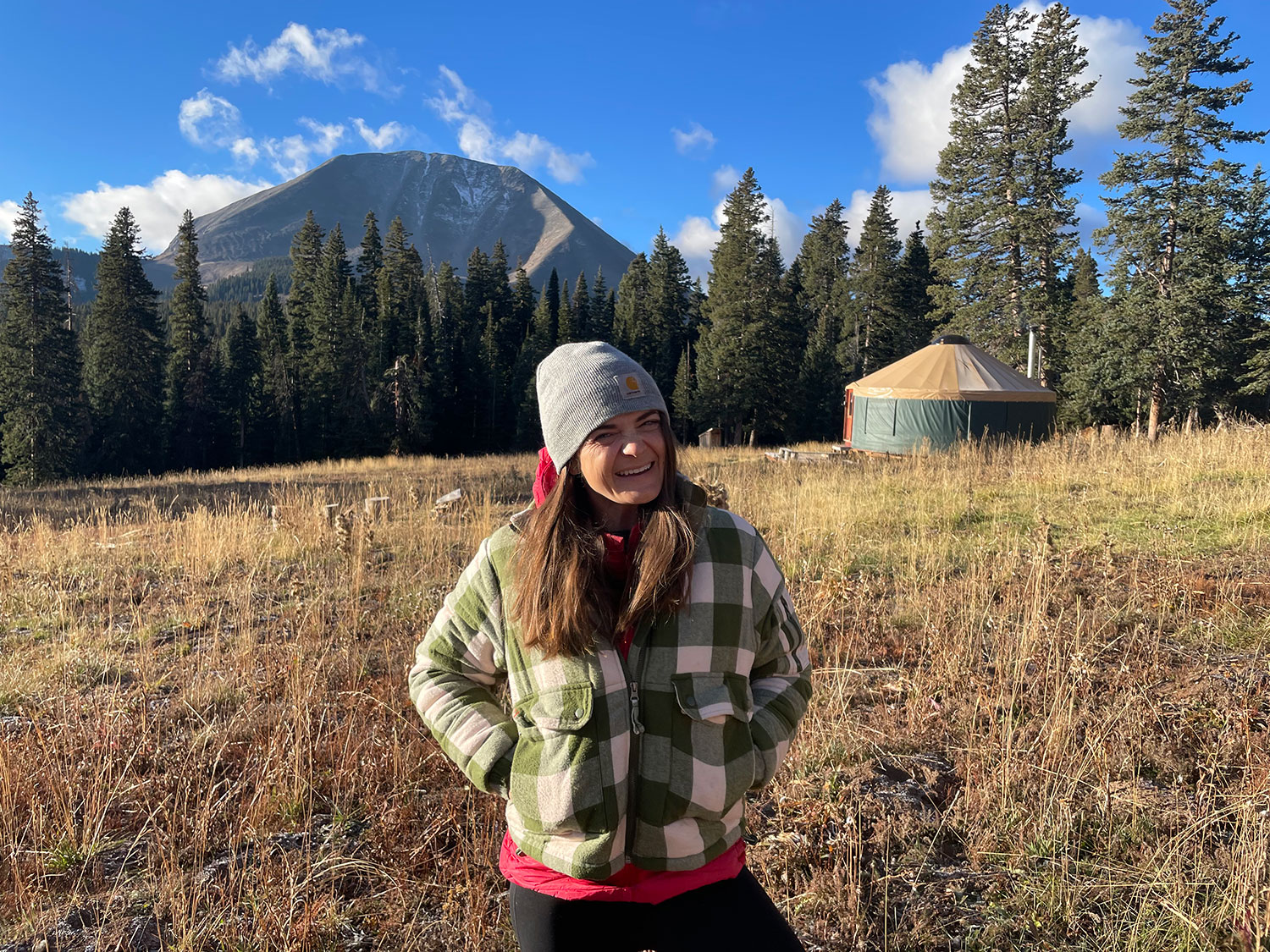 Kate LaRiviere, MD in a field with mountain and yurt in the background