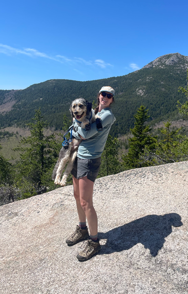 Sara Case holding her dog with mountains in the background