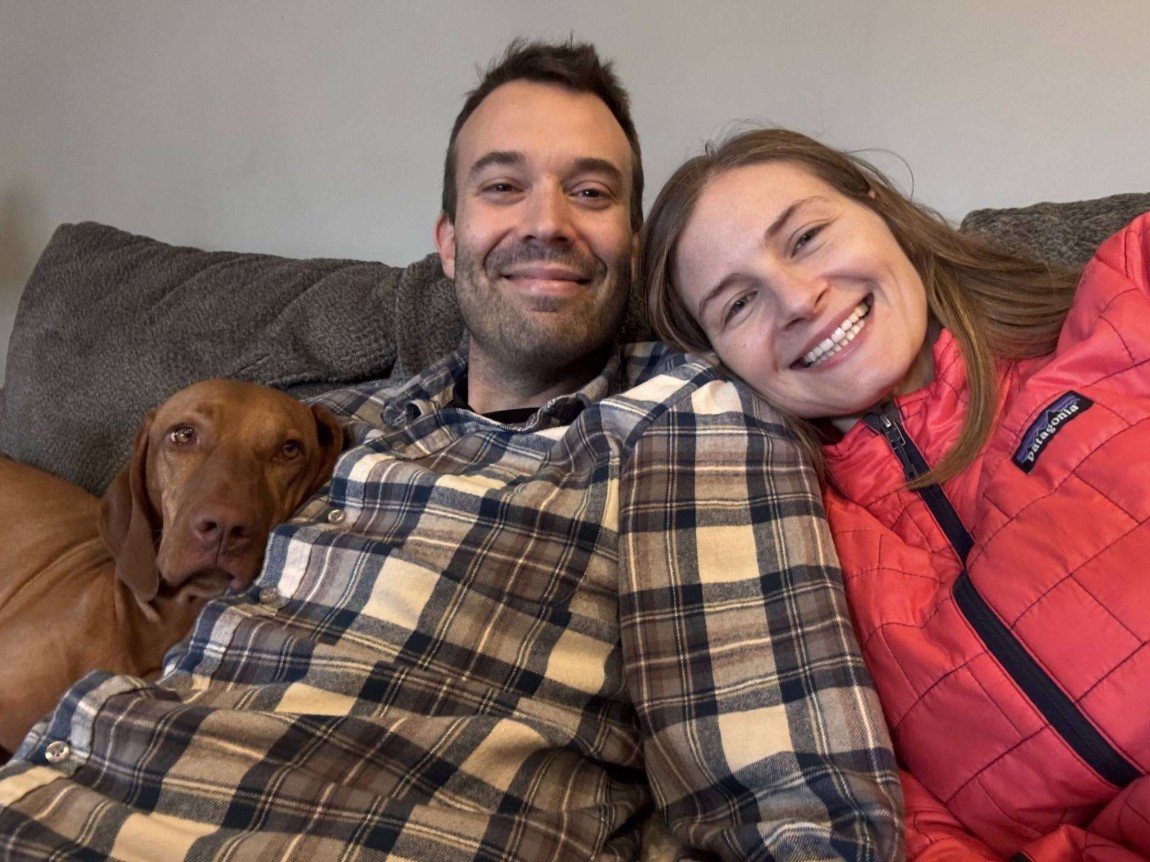 Erin Lips, MD poses with partner and her dog on the couch.