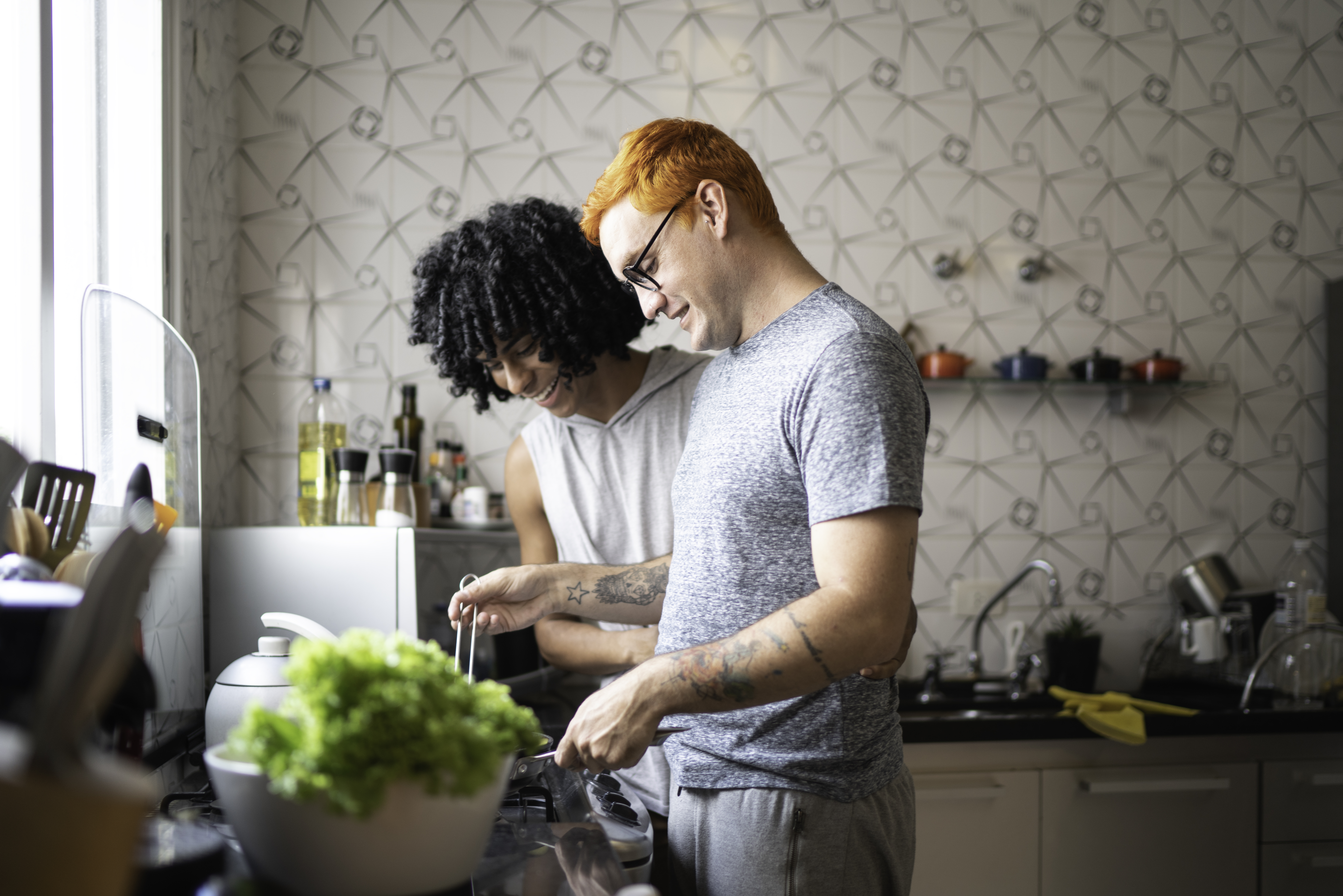 Two young men cook dinner together. 