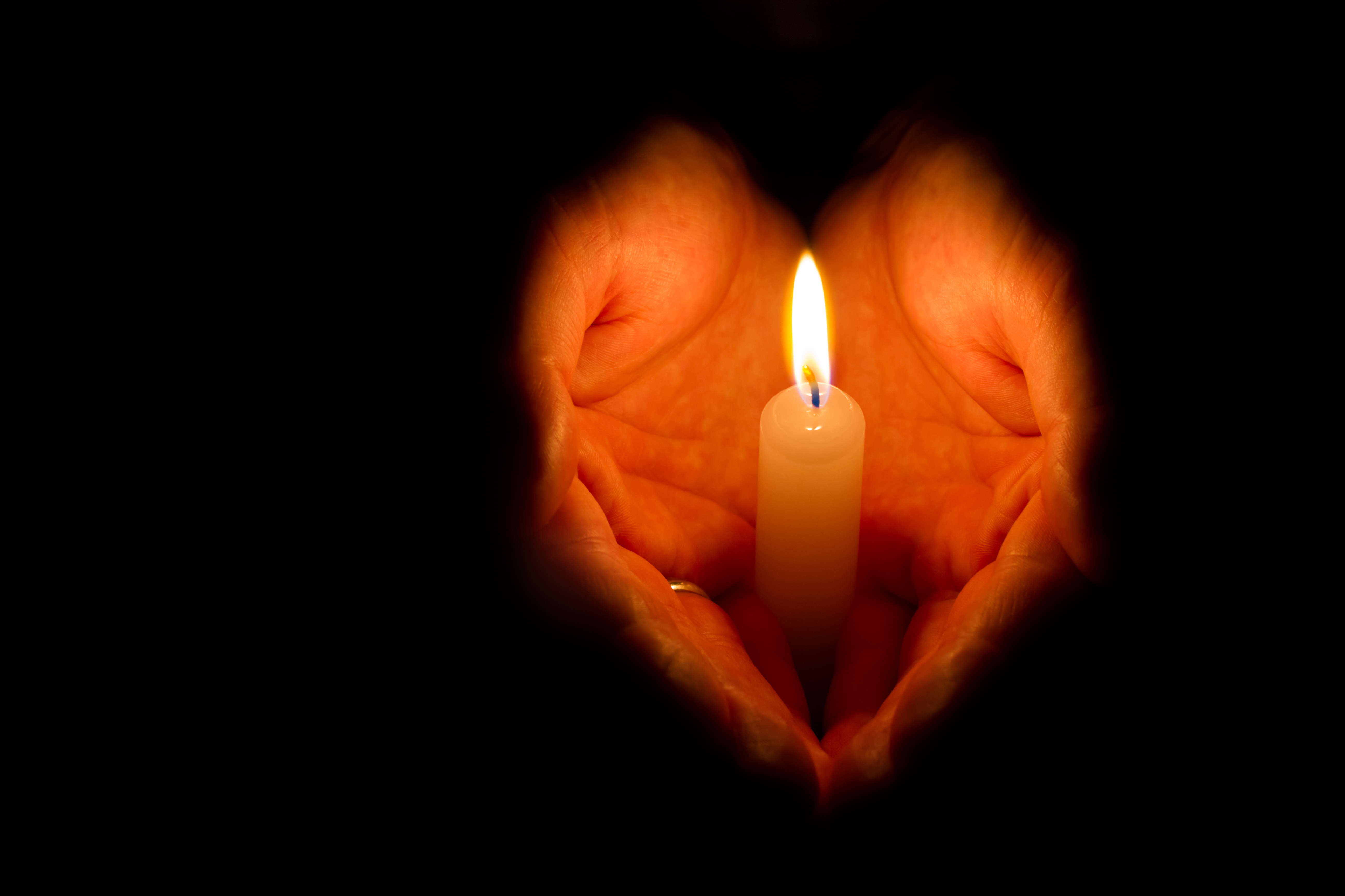 Close-up of a hand holding a lit candle.