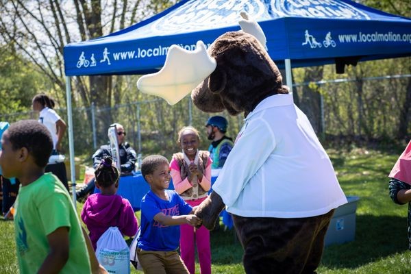 Monty the Moose mascot holding hands with child