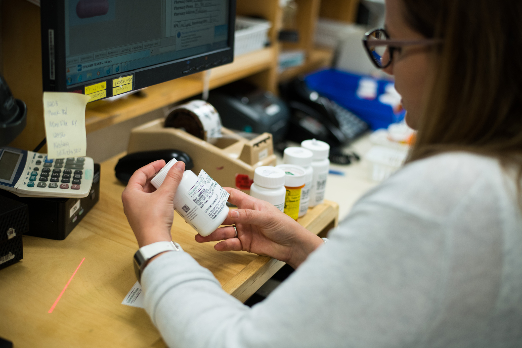 Closeup photo of a pharmacy employee examining prescription bottle