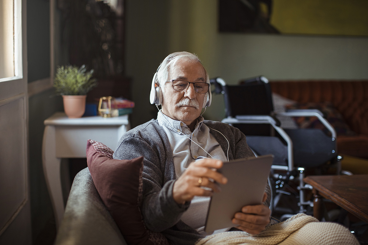 A senior man uses a tablet at home.