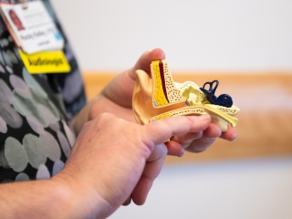 Audiology detail of woman holding a model of an ear canal.