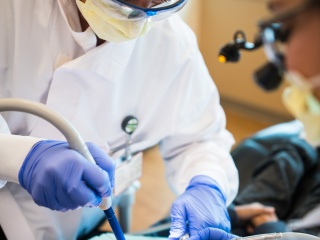A dental health specialist cleans patient teeth.