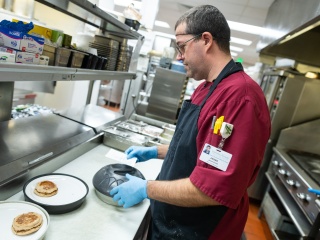 Chef works in kitchen putting together a meal for inpatient room service.