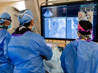 Medical providers look at a screen with results of a scan.