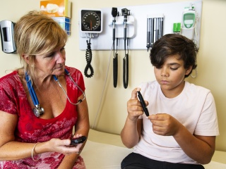 A medical provider assists a child with checking their insulin levels. 
