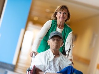 A volunteer pushes a patient in a wheelchair.