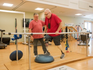 A physical therapists helps an amputee patient complete exercises.