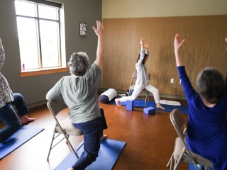 A group of seniors follows a yoga routine for pain management.