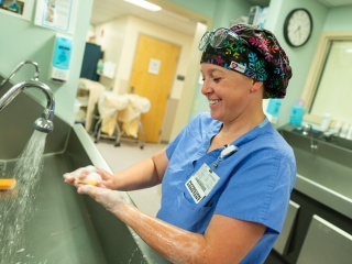 A physician assistance washes their hands in preparation for a surgery.