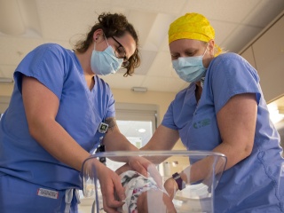 Two medical providers check on a newborn baby.