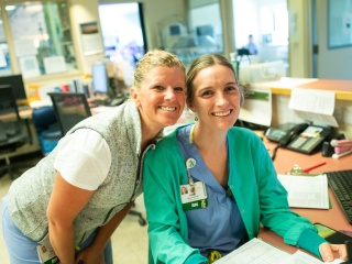 Two nurses pose and smile at the camera.