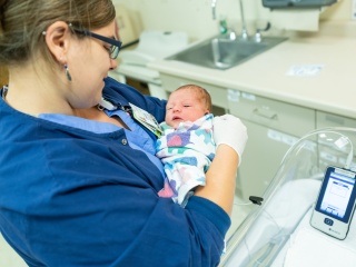A medical provider holds a newborn baby.