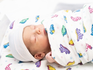A newborn baby at the Alice T. Miner Women & Children's Center lies in a bassinet. 