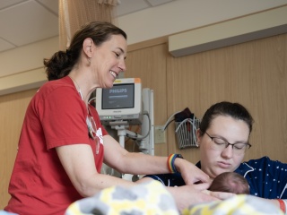 A nurse helps a mother breastfeed her newborn baby.