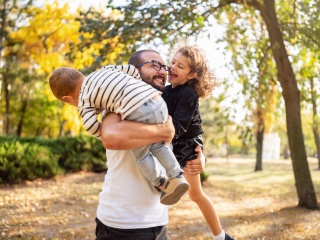 A father plays with his two children in a forest.
