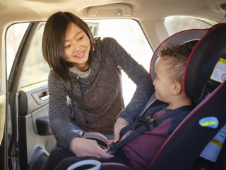 A mother buckles her child into a car seat.