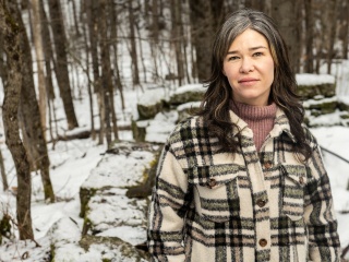 Casey Kolb Nava stands in the snowy woods in the winter.