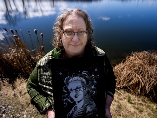 StaciAnn Grove stands with artwork by a pond.