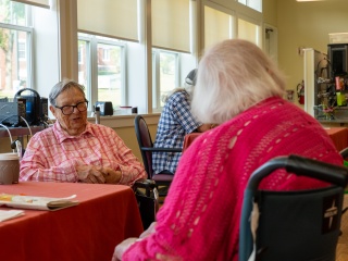 Two residents sit down at a table and talk to one another.