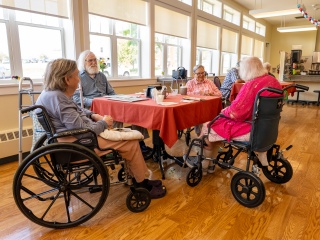A group of residents sit around a table chatting.