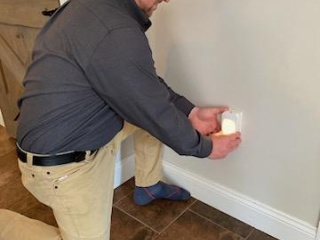 A man installs a night light in a hallway to improve safety.