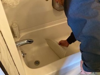 A person installs an anti-slip mat in a tub to improve safety.