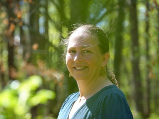 Portrait of Tawnya Kiernan outside in the trees.