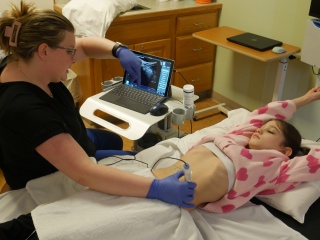 Pediatric patient Macie Hoyt lays on a hospital bed for an ultrasound on her abdomen.