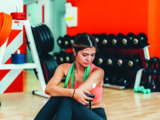 Stock photo of a woman checking her continuous glucose monitor while at the gym.