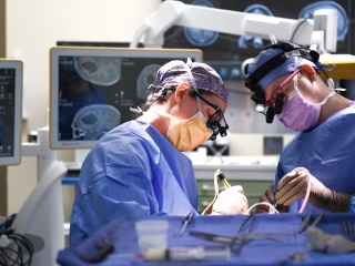 Katrina Ducis, MD, a neurosurgeon with UVM Health – UVM Medical Center, performing surgery with Dylan Adams, MD, senior neurosurgery resident.