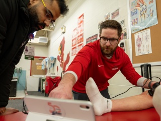 Dr. Joe Tousignant performs an ultrasound on an athlete’s knee at SUNY Plattsburgh. Observing is Rishabh “Sunny” Taneja, MD, first-year family medicine resident at Champlain Valley Physicians Hospital.