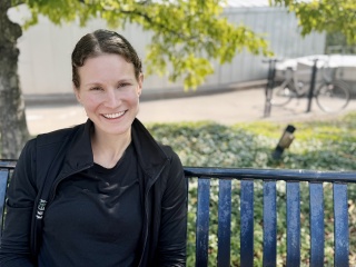 Portrait of Tori Constantine sitting on a bench outside.