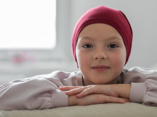 Photo of smiling child wearing a head scarf in the hospital.