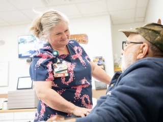 A medical provider smiles and speaks with a cancer patient.