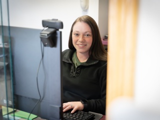 A front desk staff smiles at the camera.