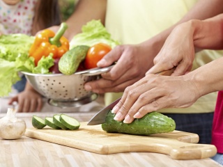 Stock photo of adults cutting vegetables for cooking.