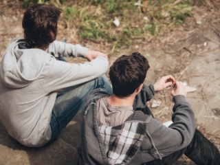Two men sitting together outside looking away from the camera.
