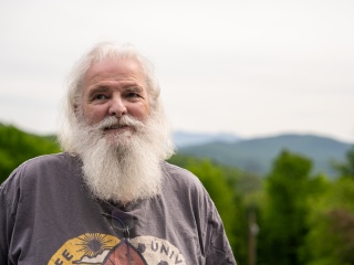 Portrait of John Kohlmeyer standing outside with mountains behind him.