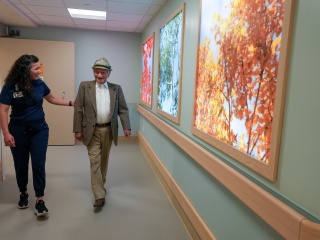 A patient and a medical professional walk down a hall together.