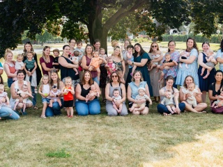 A group of women and their children pose and smile for the camera.